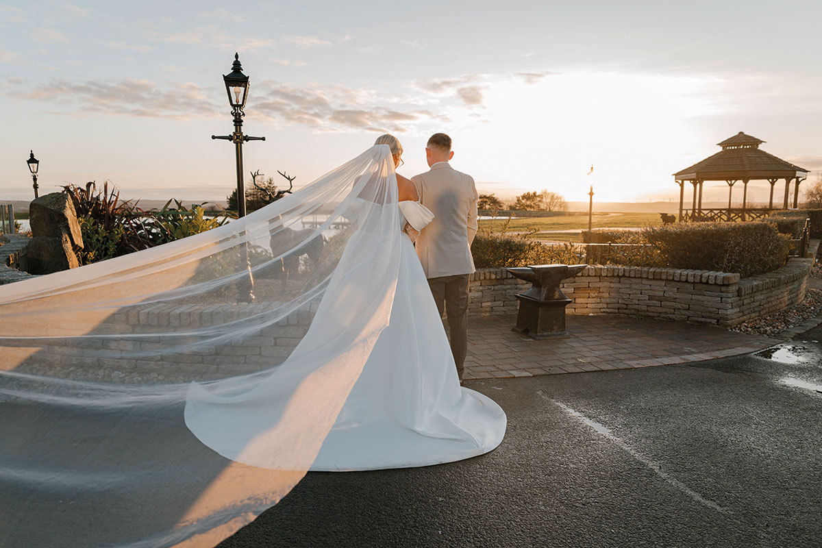 Bride and groom walking through the grounds at The Vu during golden hour with the bandstand in the background