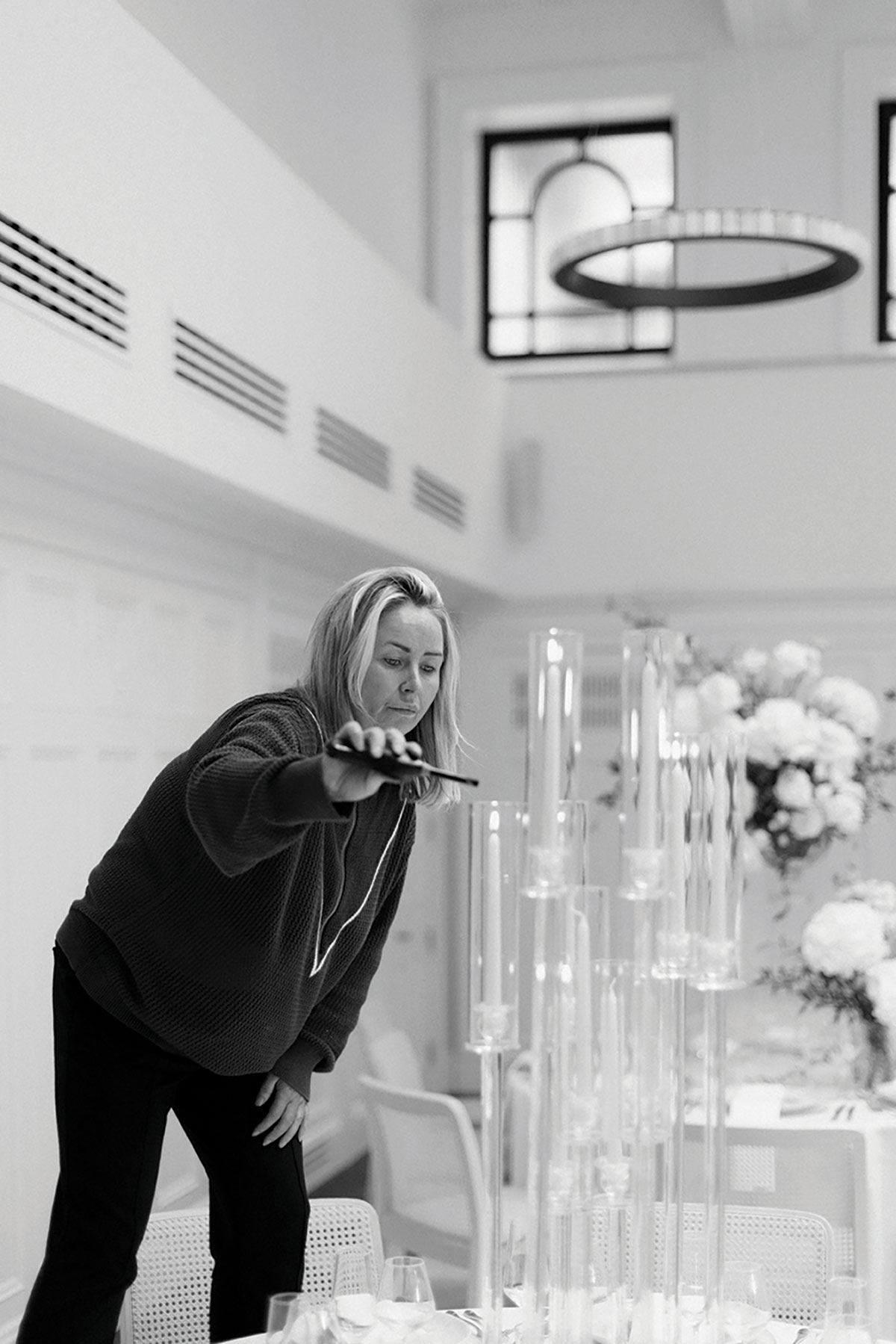 Wedding florist arranging tall glass candle holders in luxury Glasgow wedding venue
