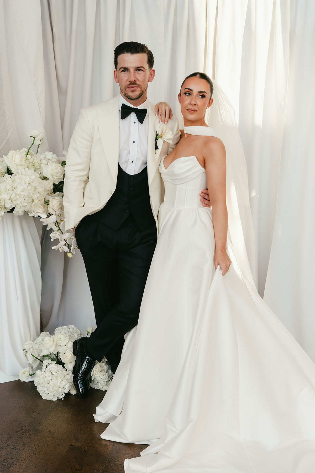 Bride and groom portrait with white draped backdrop and floral styling at Enterkine Country House