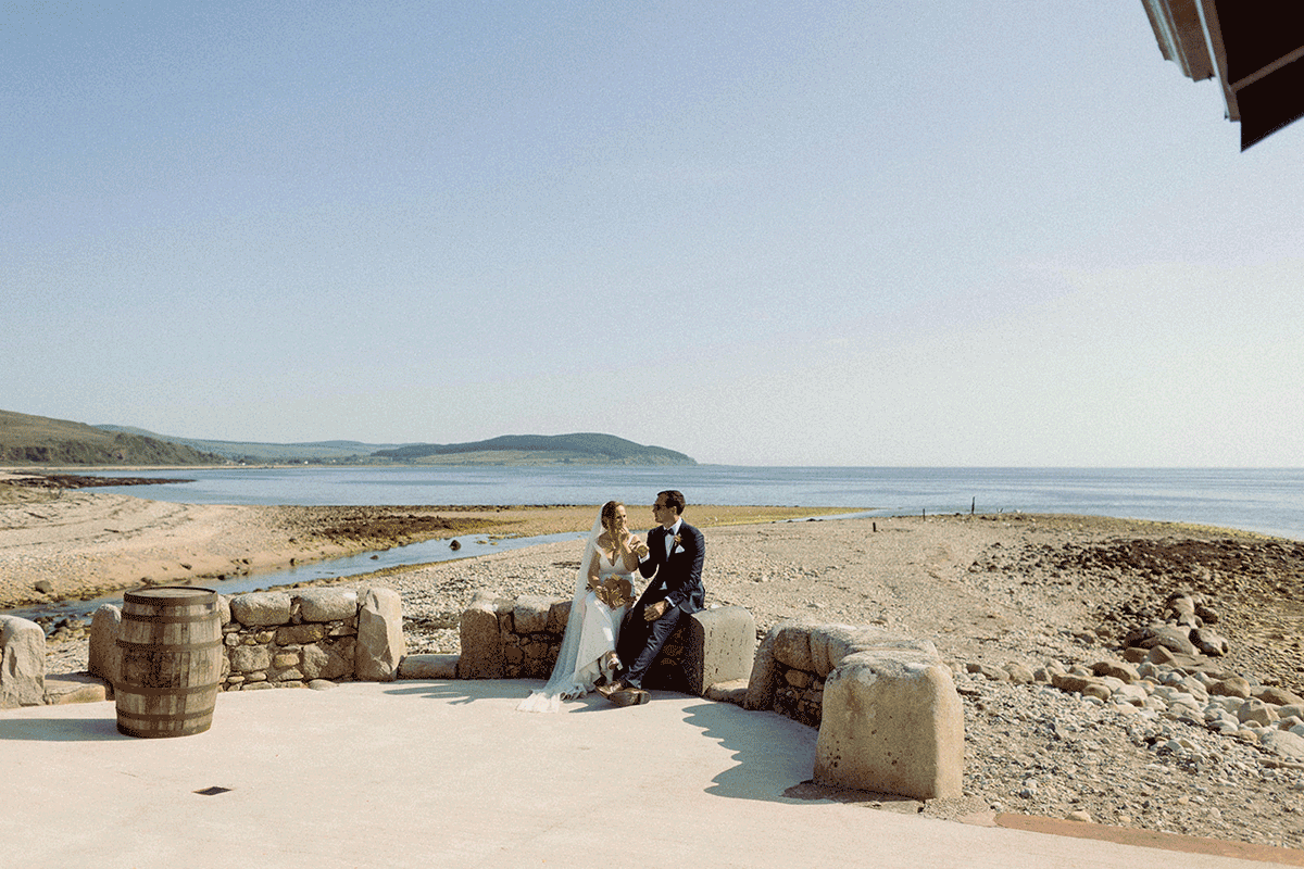 Bride and groom sitting outside by the water
