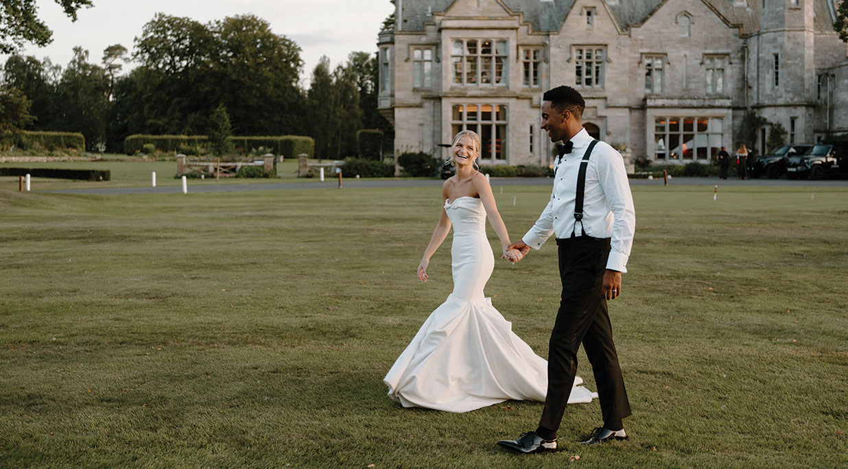 bride and groom holding hands and smiling in front of SCHLOSS Roxburghe