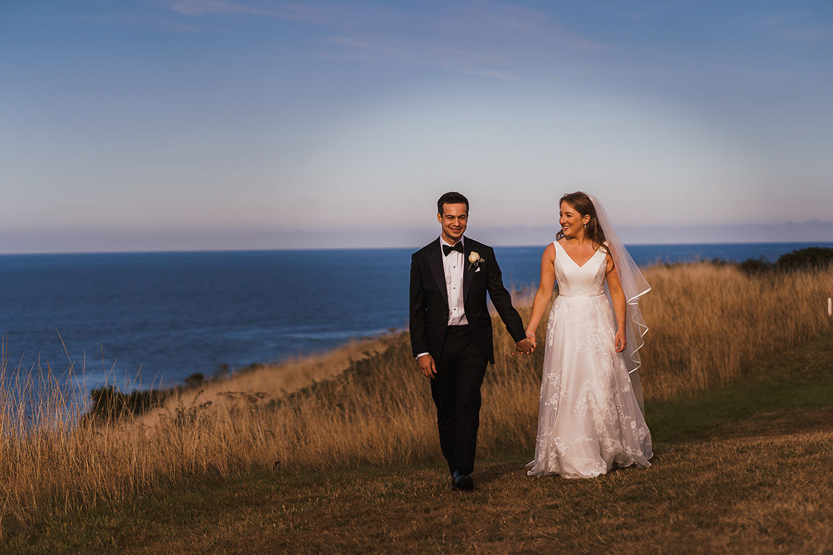 Bride and groom walking by the coast at Fairmont St Andrews with views across St Andrews Bay