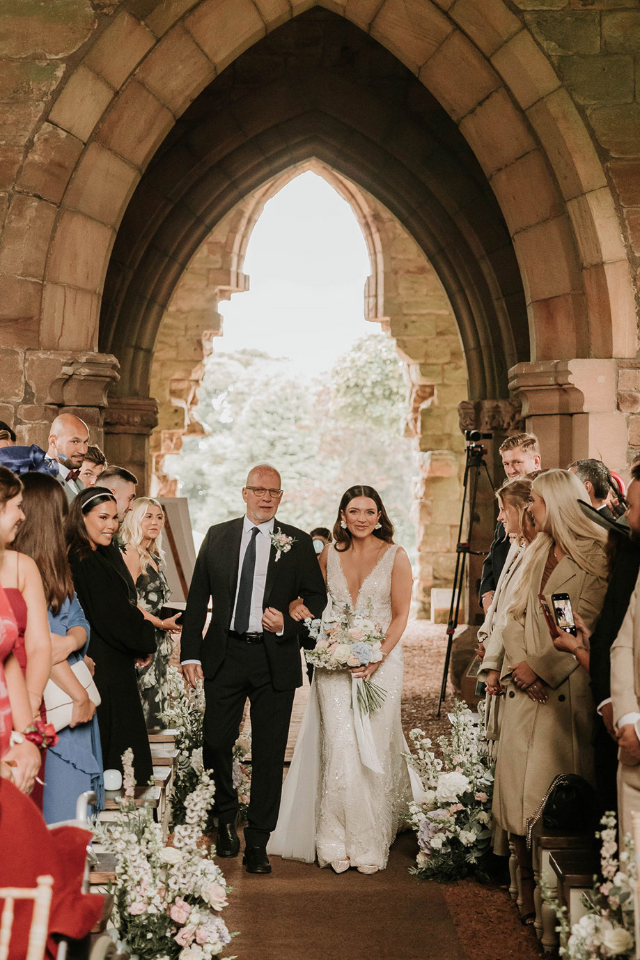 a bride entering a wedding ceremony on the arm of a man a suit in church at Dunglass Estate