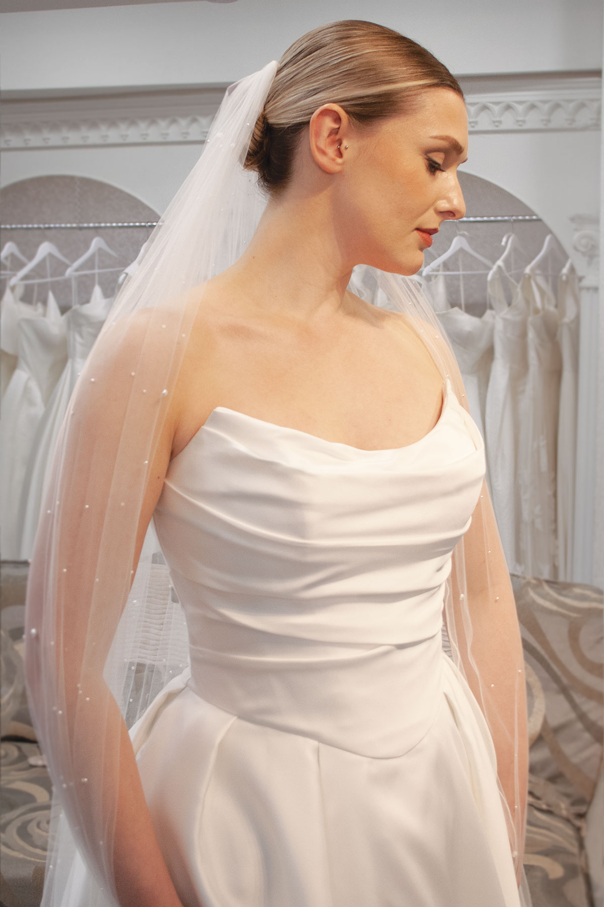 portrait photo of a bride with a slickback bun, long pearl-studded veil and a strapless corset bodice ballgown wedding dress