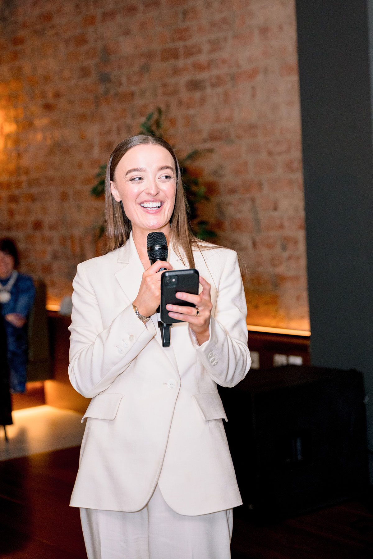 Bride in white suit giving wedding speech at Glasgow wedding reception.