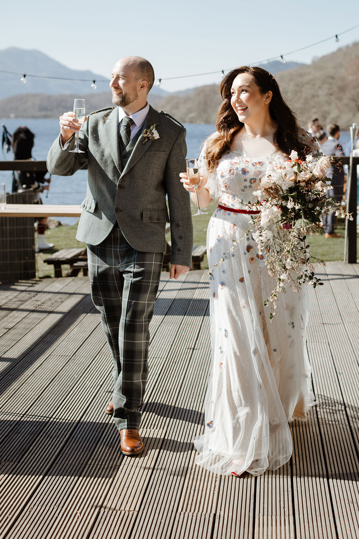 Bride and groom walking, smiling and holding glasses of champagne 