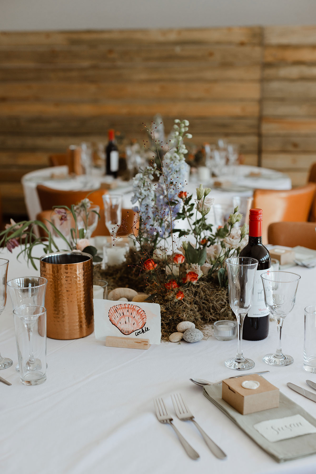 Table setting with place cards, wine and floral arrangement centre pieces 