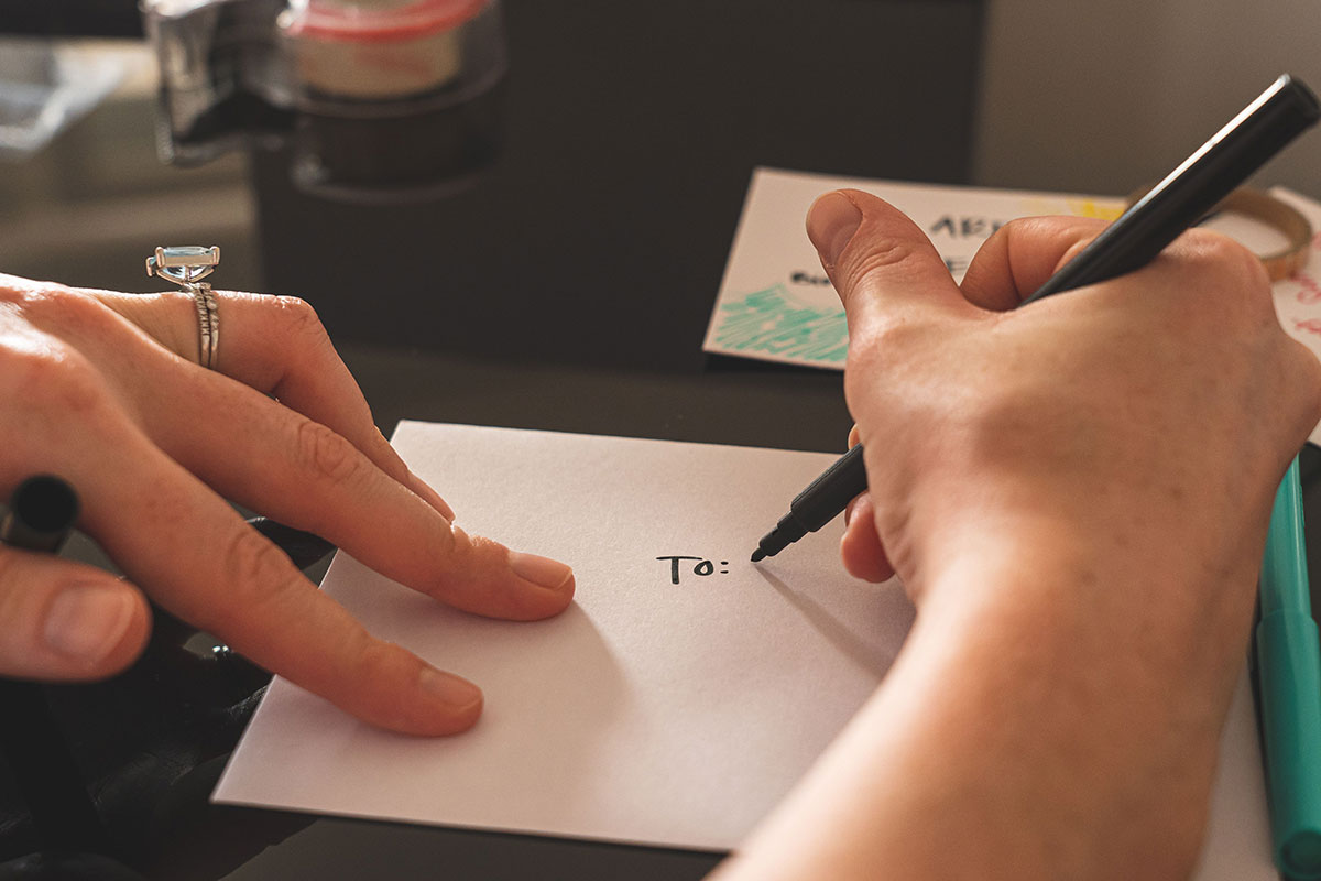 Close-up of someone beginning to write a personal message inside a wedding card.