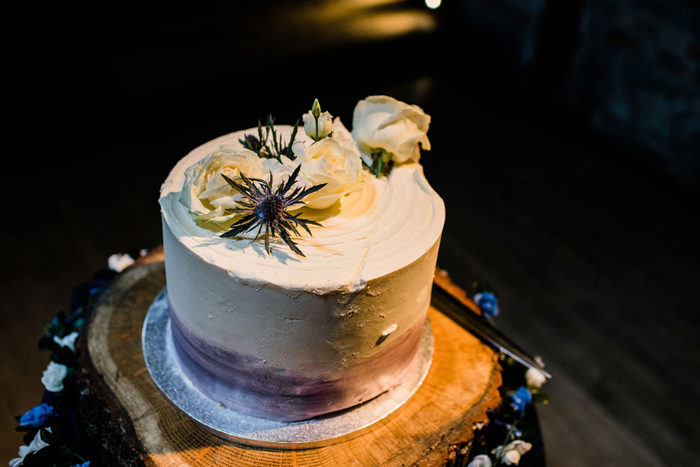 Wedding cake with white icing and white roses and thistles on top