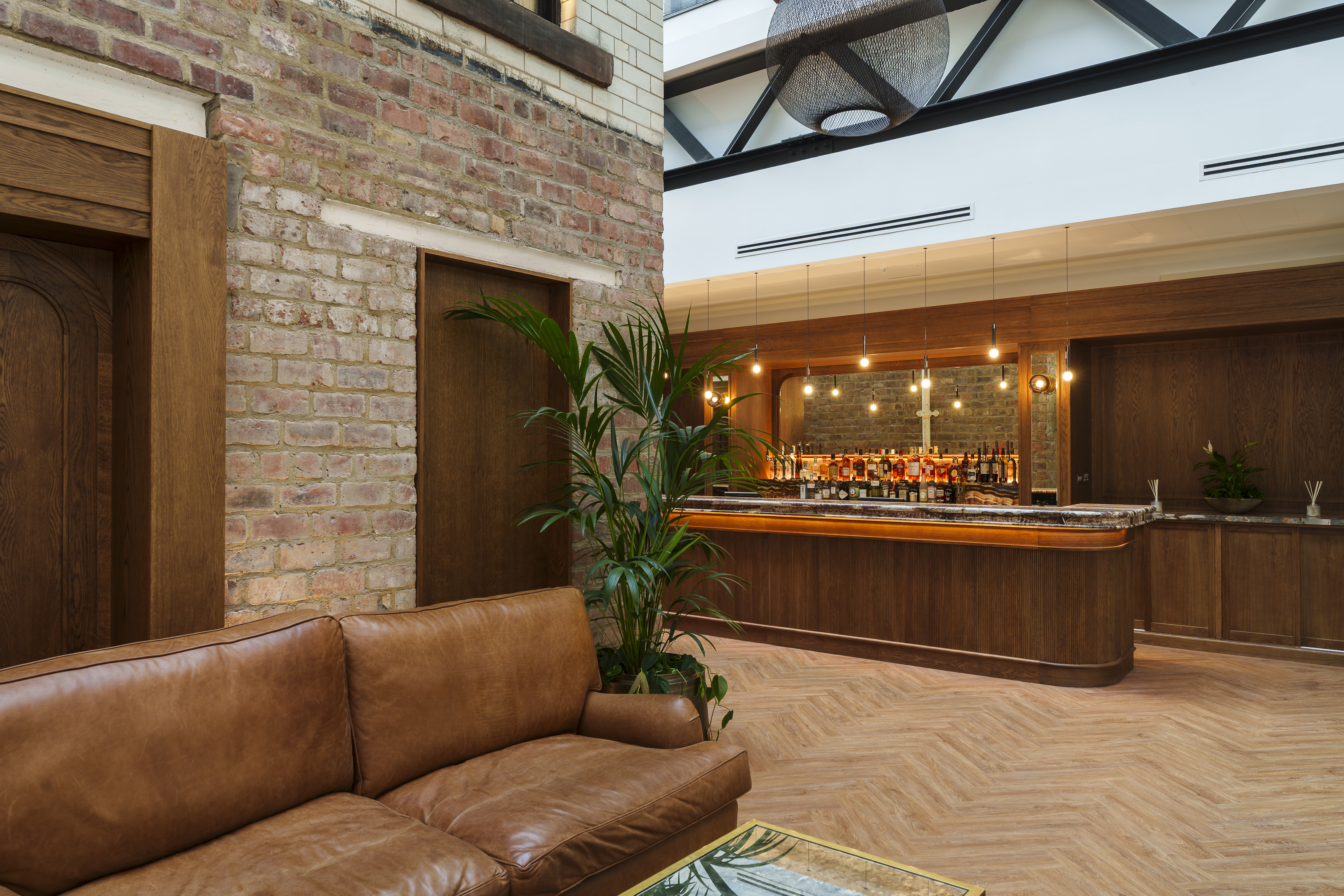 The Collector's Hall's courtyard and bar area with marble decor and tan leather couch