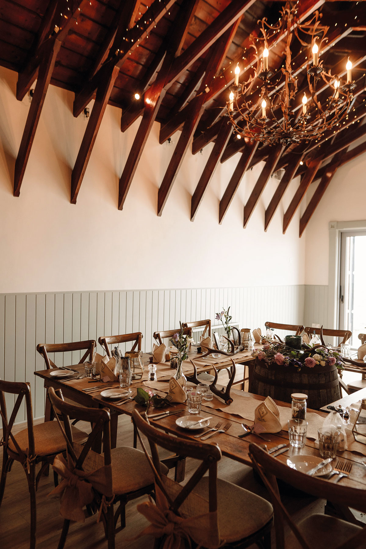 Rustic wedding reception at Dougarie Boathouse on the Isle of Arran with wooden tables and antler centrepieces
