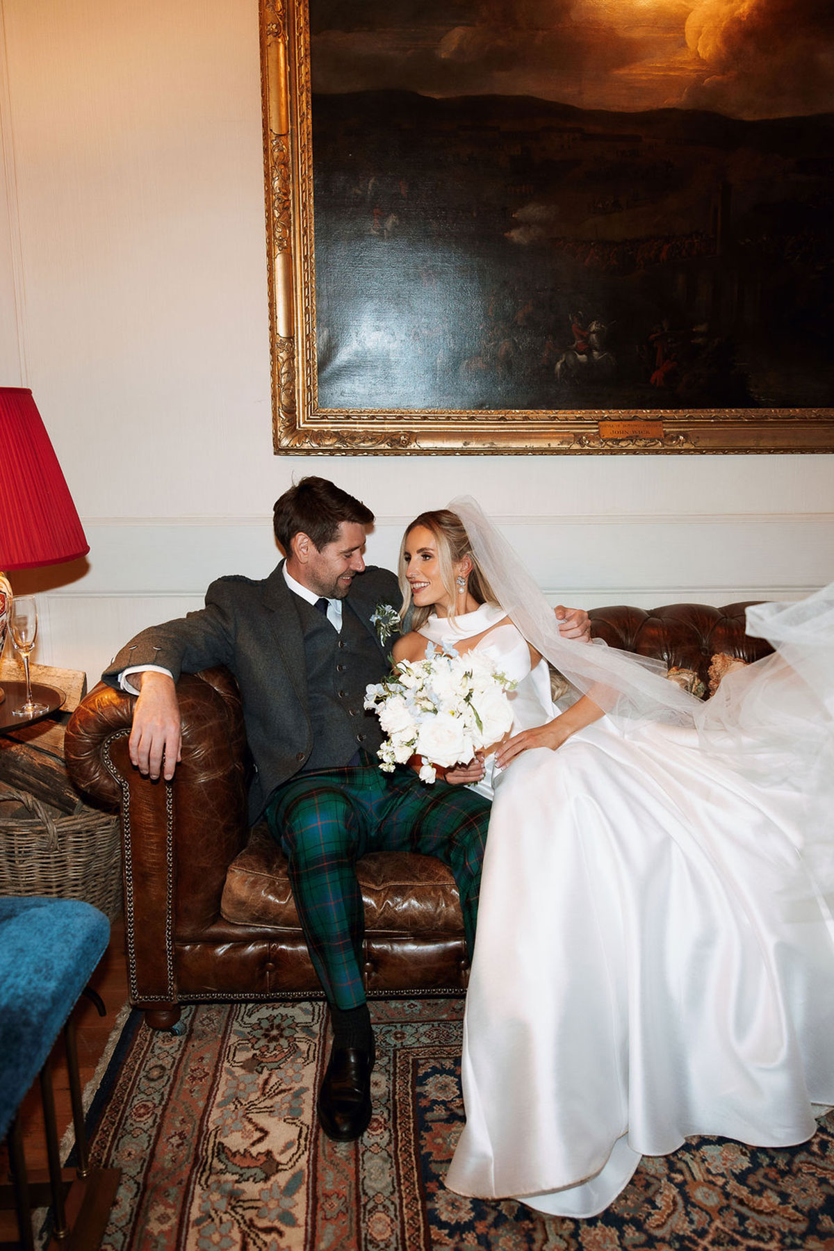 Bride and groom relaxing on leather sofa at Rosebery House Edinburgh wedding venue