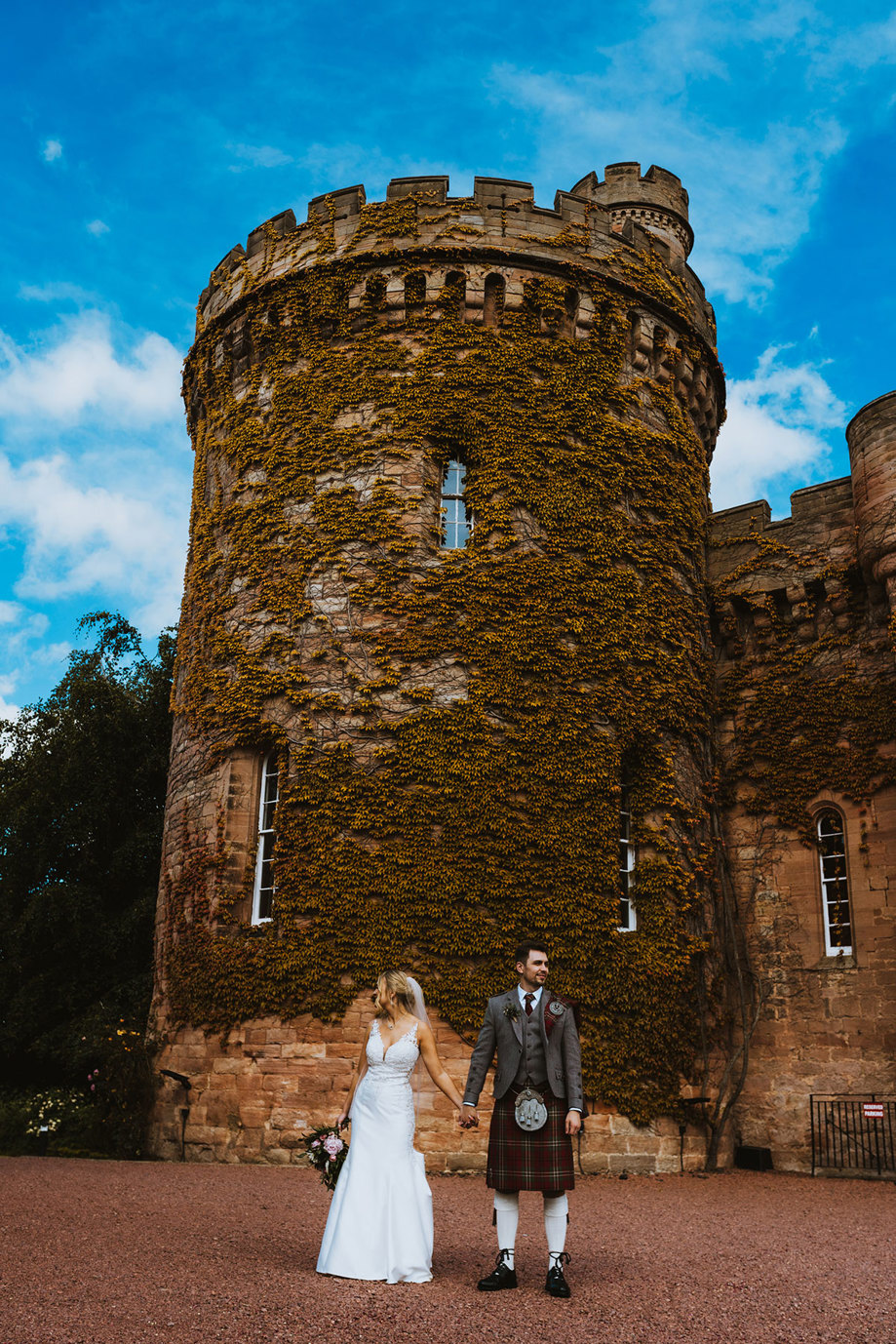 exterior of dalhousie castle with bride and groom standing in front