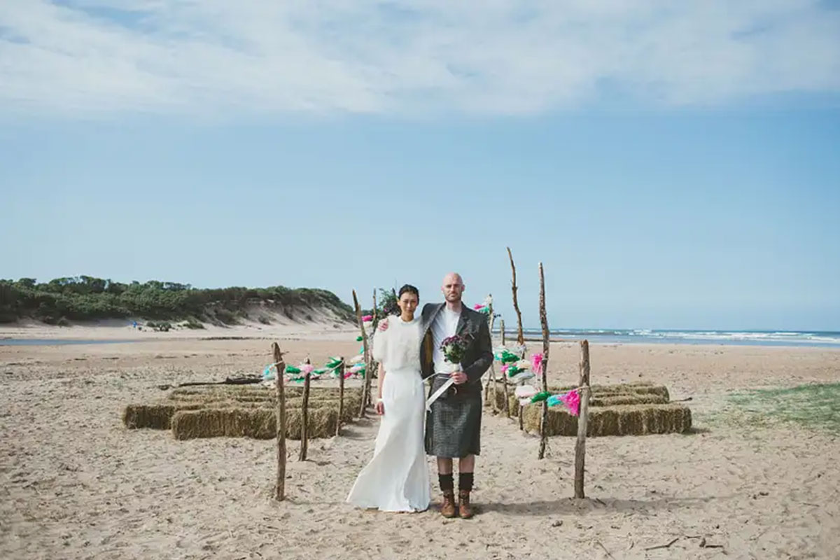 Outdoor beach wedding ceremony setup at Harvest Moon Weddings with hay bale seating on the sand.