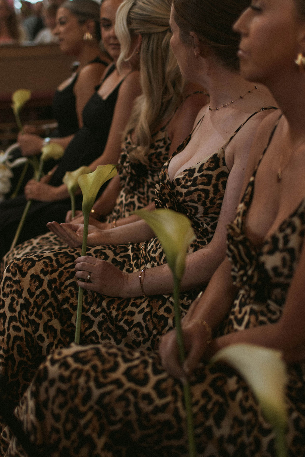 Bridesmaids in leopard print dresses holding calla lilies during wedding ceremony at Kilwinning Abbey Church, Ayrshire.