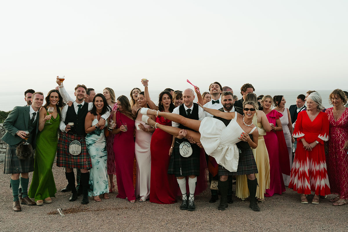 Group wedding portrait with sea in background at Kinkell Byre in Fife.