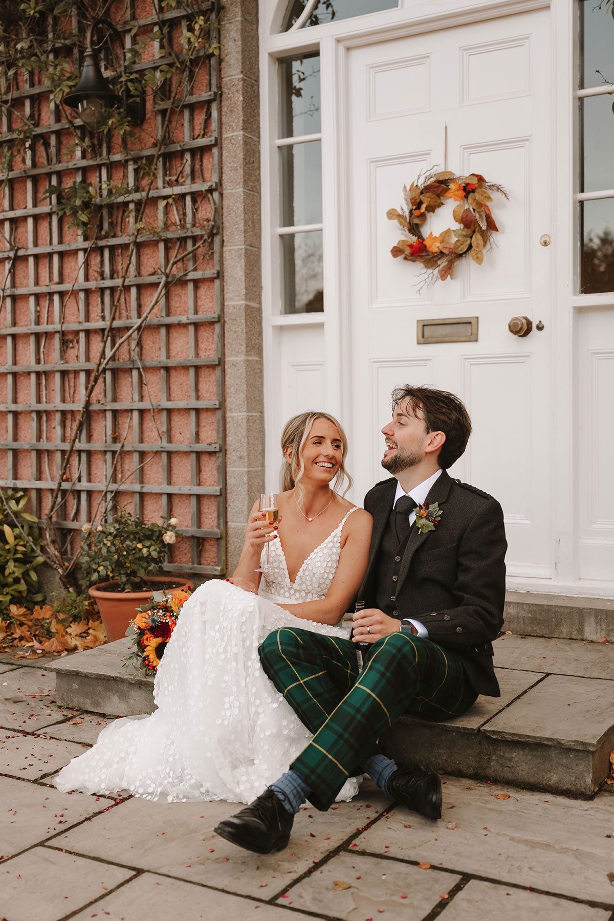 Bride and groom sitting on a doorstep laughing together