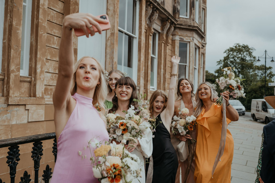 Bridesmaid takes a selfie of bridesmaids and bride