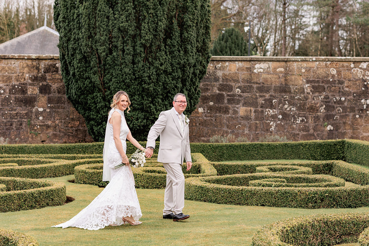 bride and groom walk hand in hand through chatelherault park