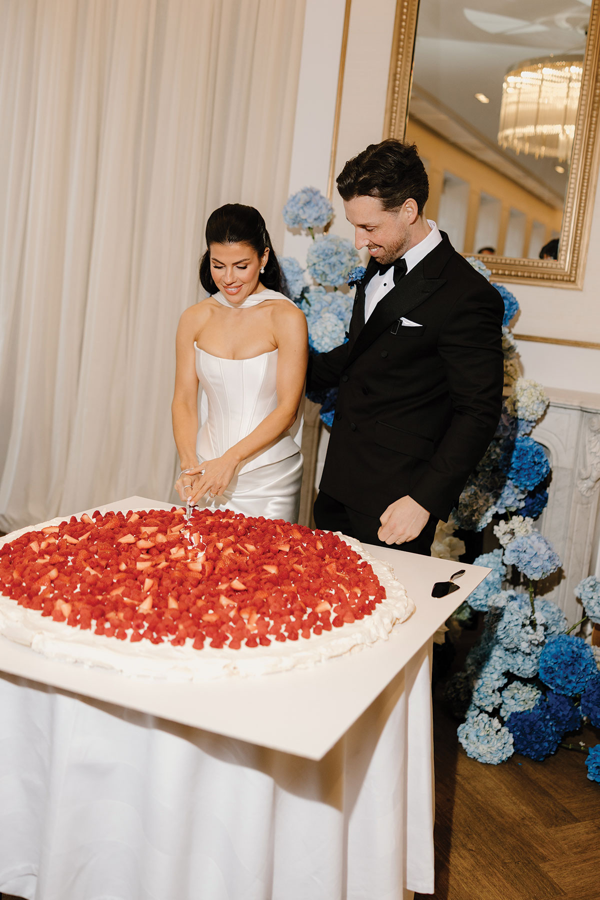 Bride and groom cutting large strawberry wedding cake at The Exchange Glasgow with blue floral backdrop