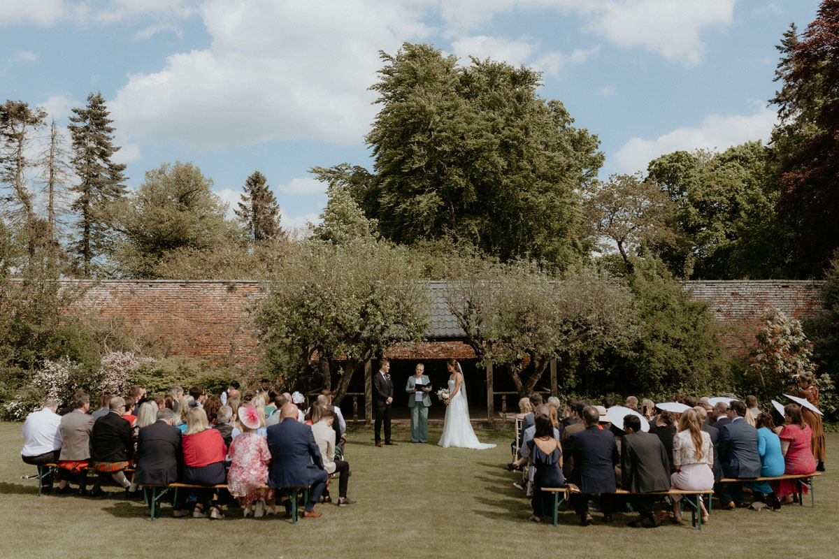 Wide view of an outdoor wedding ceremony in the gardens at The Byre at Inchyra in Perthshire.