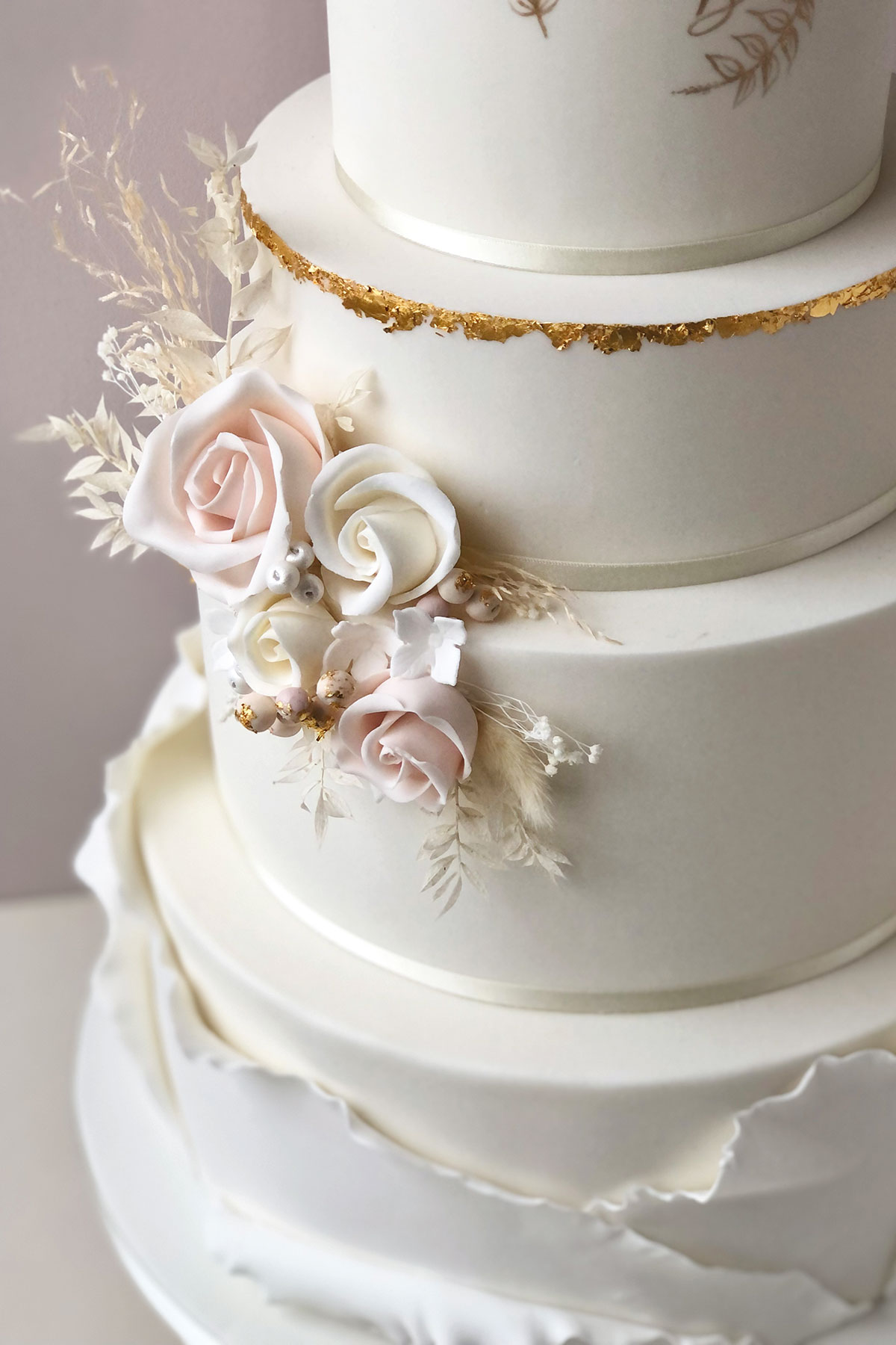 Elegant ivory wedding cake with sugar roses, gold leaf trim and textured ruffle detailing, handcrafted by Liggy’s Cakes in Glasgow