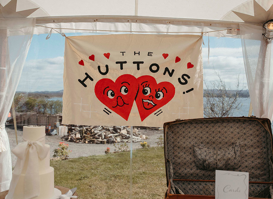 a hanging canvas banner reading 'The Huttons' with illustrated red cartoon hearts on it