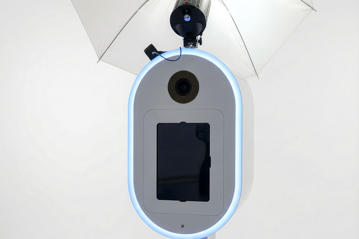 Close-up of modern white photo booth with circular LED light ring, camera lens and touchscreen display