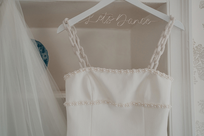 A Close Up Of A Wedding Dress On A Hanger That Reads 'Let's Dance'