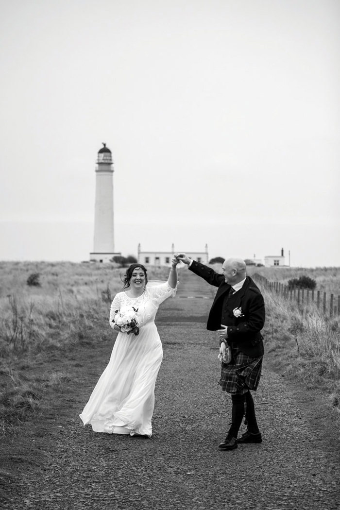Black and white picture of bride and groom dancing outdoors at wedding