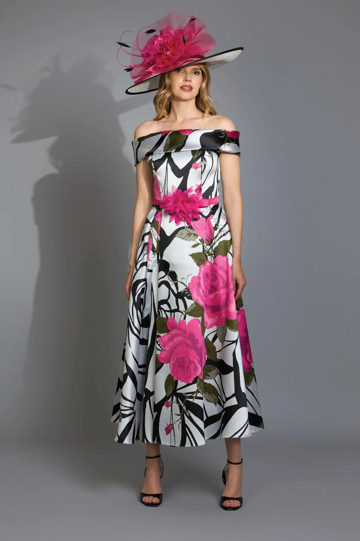 Floral mother of the bride midi dress in pink, black and white, styled with a pink statement hat.