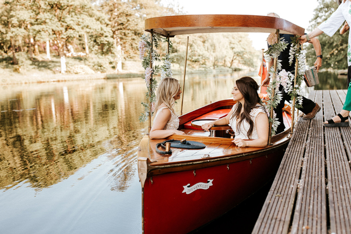 Two brides sit in a boat on the water