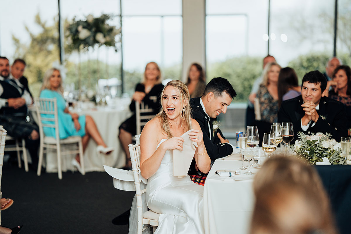 A person in a white dress sitting at a table with a person in a tuxedo.