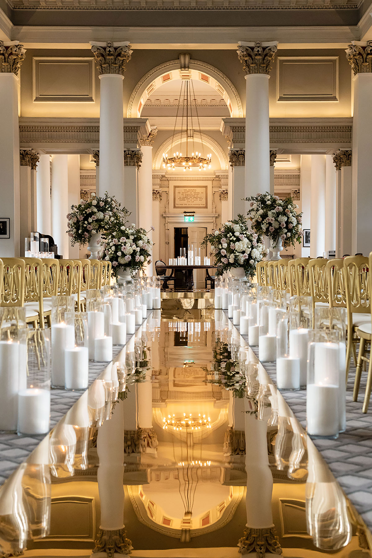Signet Library wedding ceremony setup with columns, floral urns and candlelit aisle by jordana events