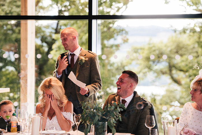 Bride and groom laugh during best man's speech
