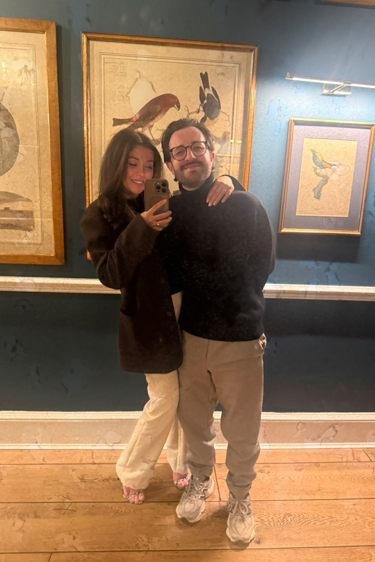Couple taking a mirror selfie in a stylish boutique hotel wearing neutral-toned outfits during a city break