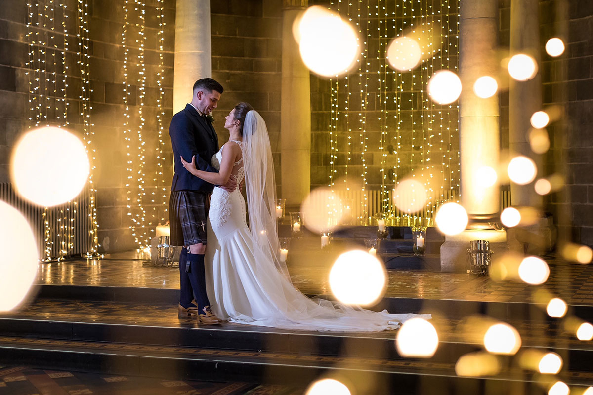 Bride and groom share a romantic moment beneath cascading fairy lights inside the grand Mansfield Traquair in Edinburgh.