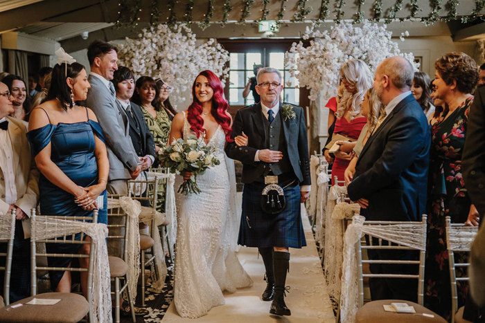 Bride with red hair and a father figure walk down the aisle