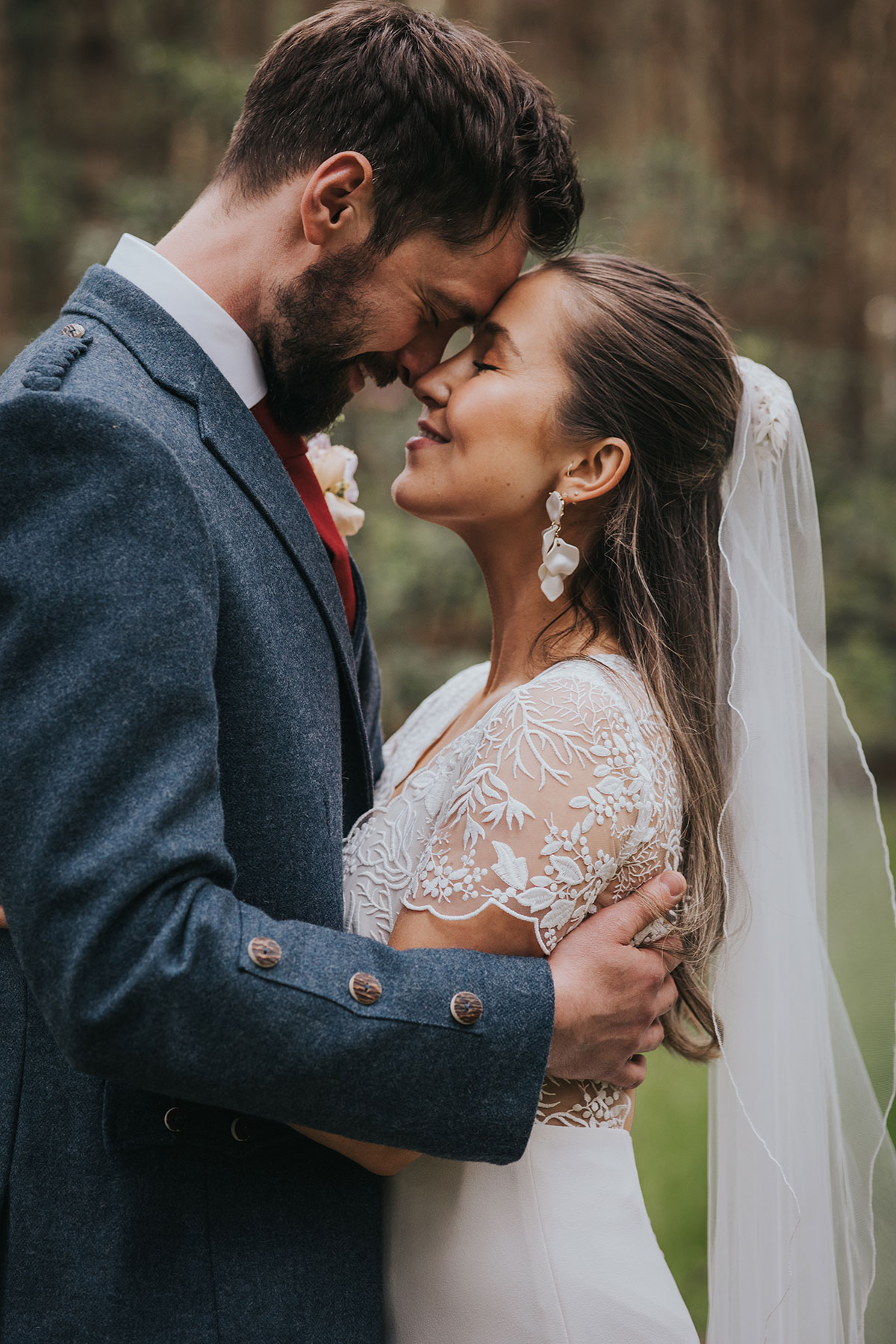 close up of bride and groom hugging with harvest moon weddings woodland in the background