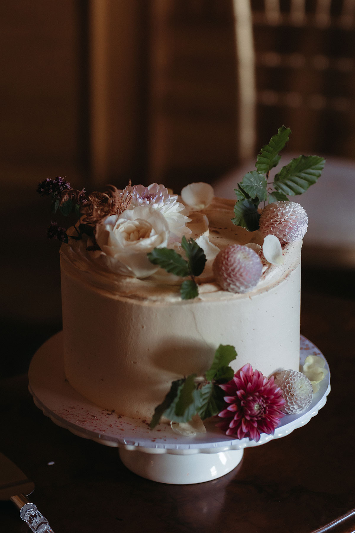 a small ivory buttercream wedding cake decorated with flowers