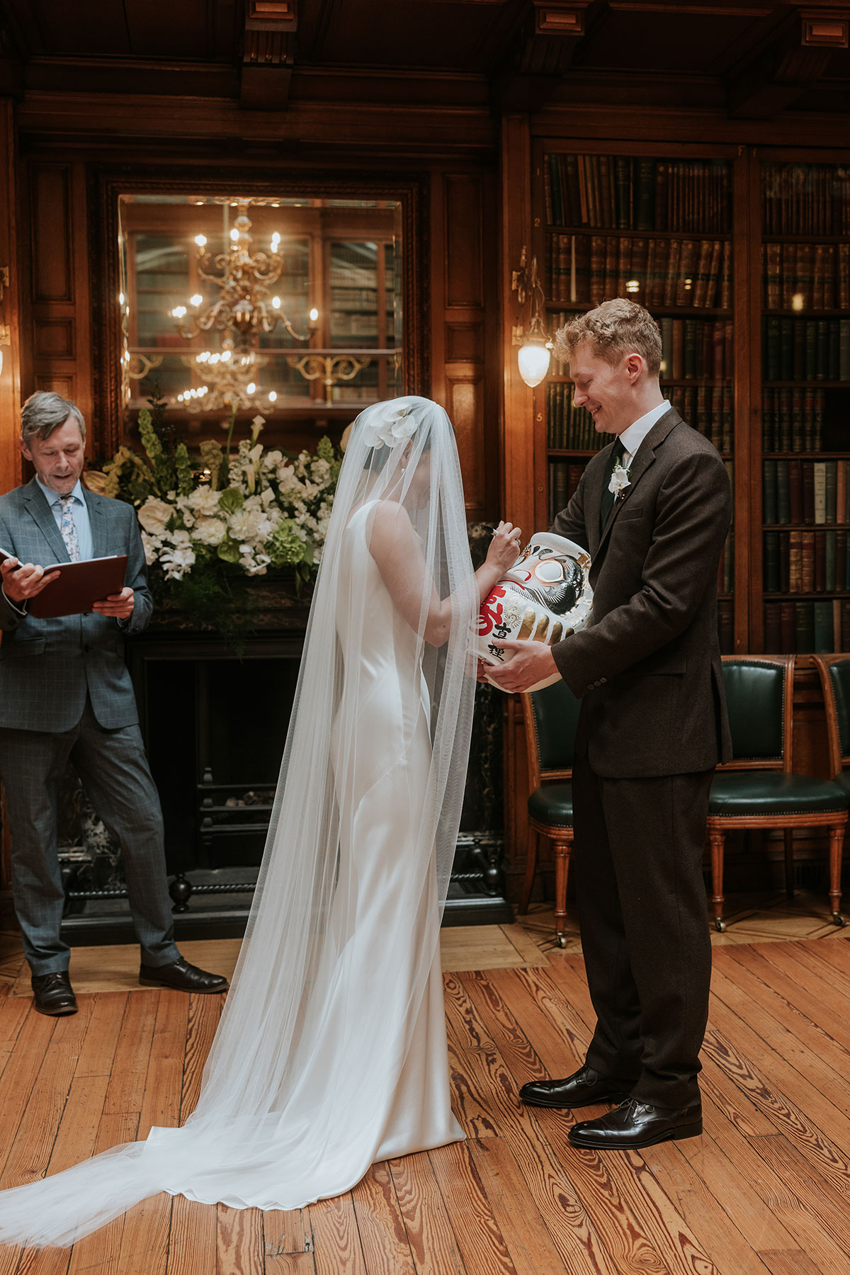 Bride signing a symbolic item while groom holds it during wedding ceremony.