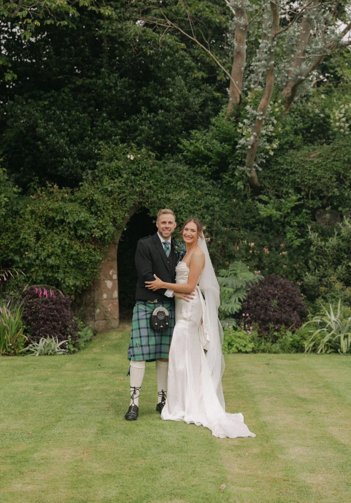 Isobel and Gary pose together in the gardens during their wedding at The Dougarie Boathouse on Arran.