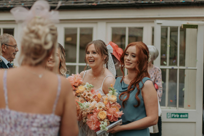 Bride laughs amongst bridesmaid and guests