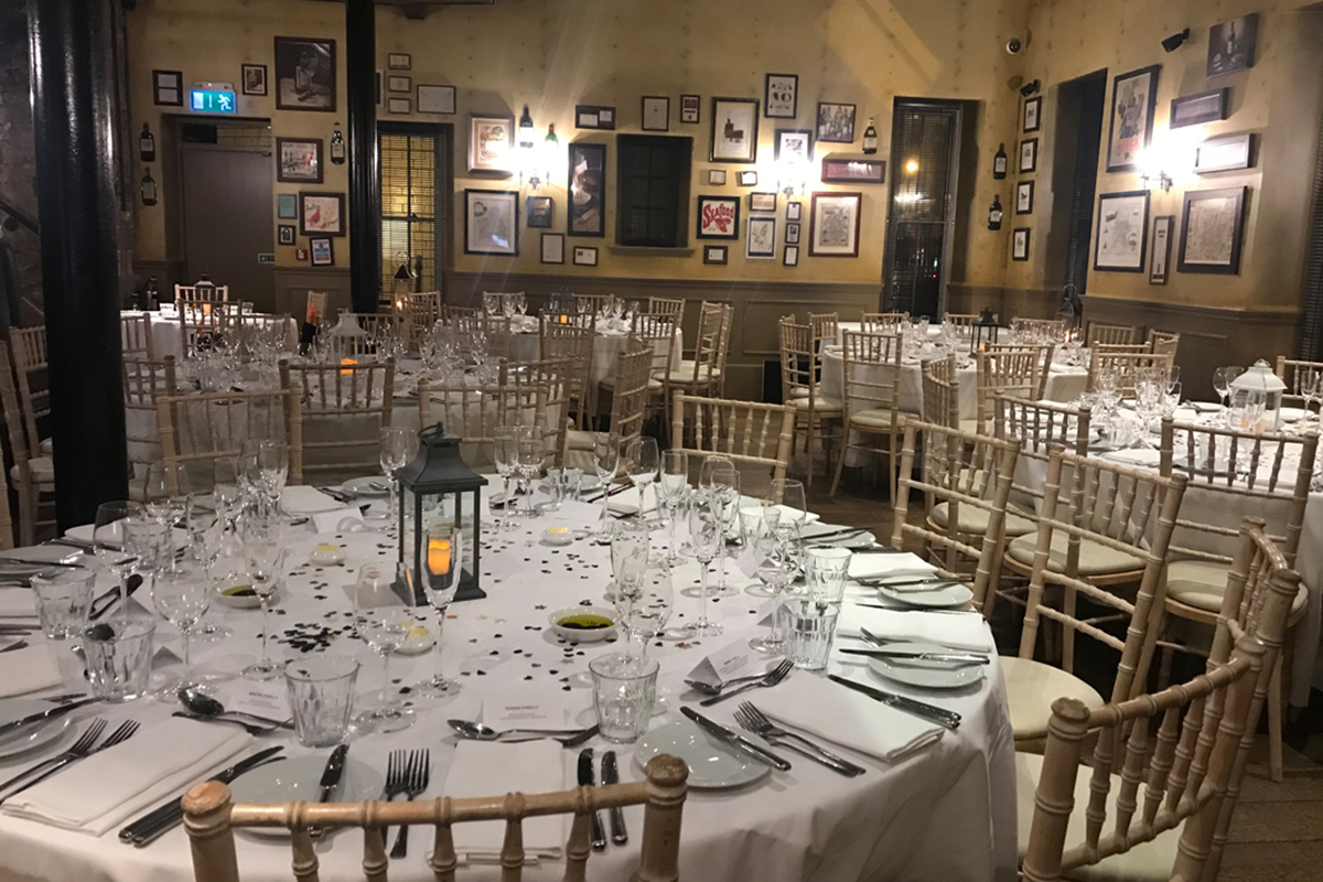 Round tables set for a wedding meal in a cosy bistro with framed art on the walls