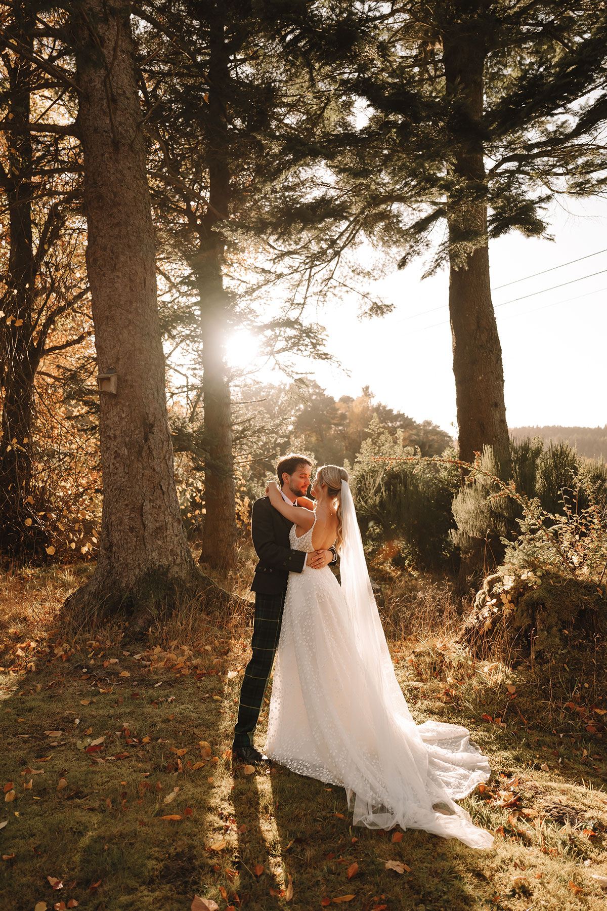 bride and groom hug at ballogie house as sun sets behind them