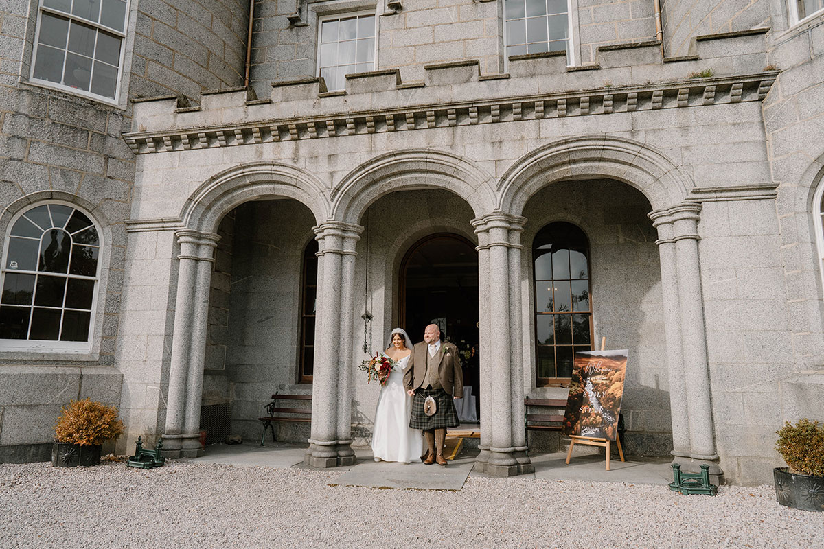 Bride and groom walking out of Cluny Castle after their autumn wedding ceremony in Aberdeenshire.