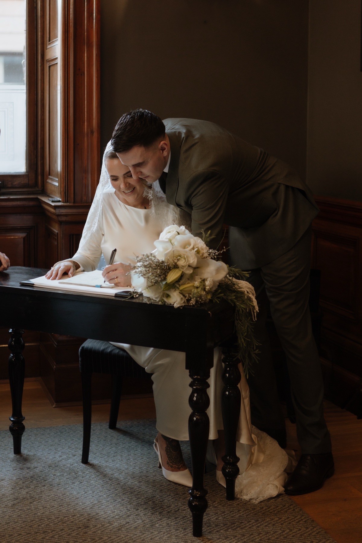 Bride signing the wedding register with the groom beside her at 23 Montrose Street in Glasgow.