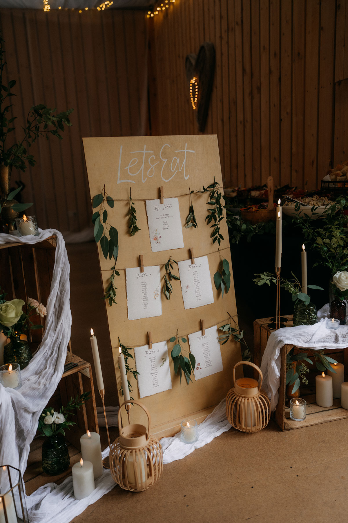 Rustic wedding seating plan display with candles, foliage and handwritten table cards