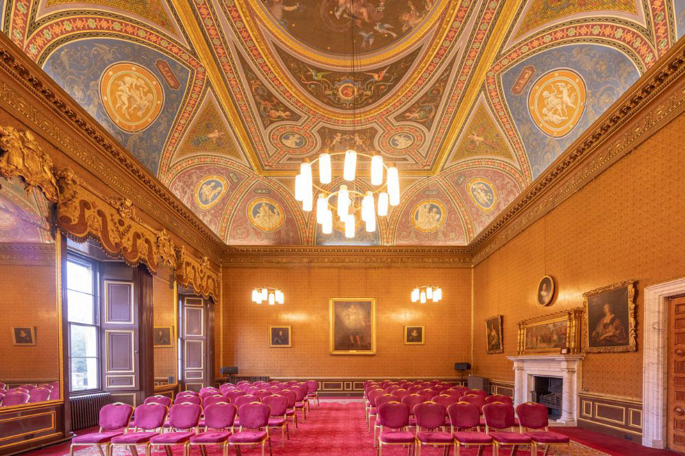 Newbattle Abbey Drawing Room set for a wedding ceremony with ornate painted ceiling, fireplace and rows of chairs