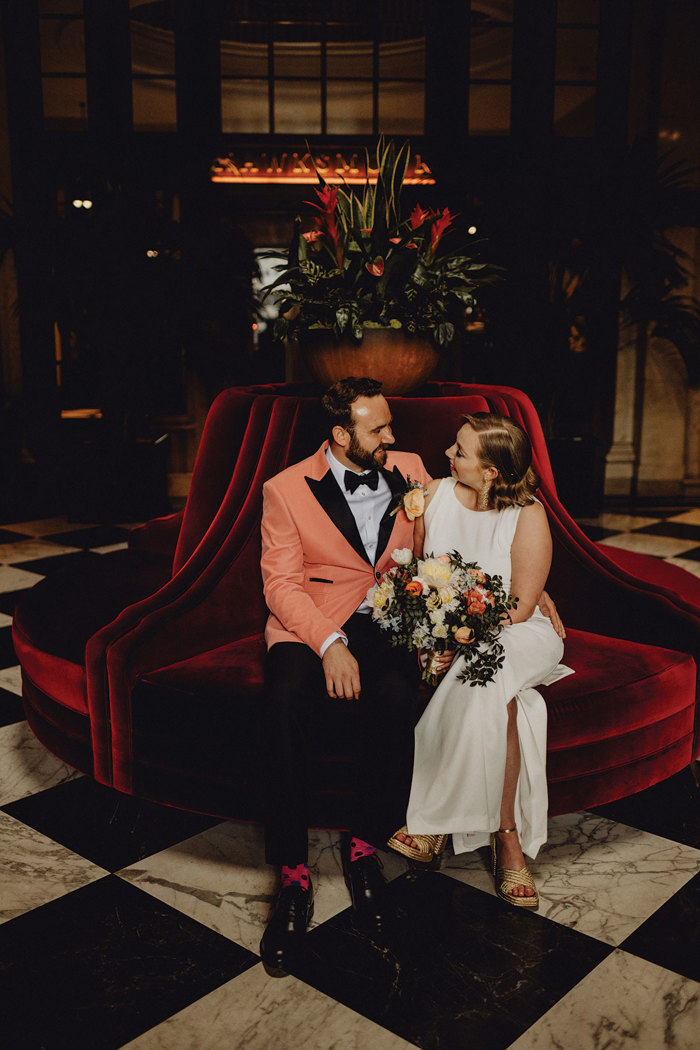 A person and person sitting on a red velvet couch in the lobby at Cheval the Edinburgh Grand.